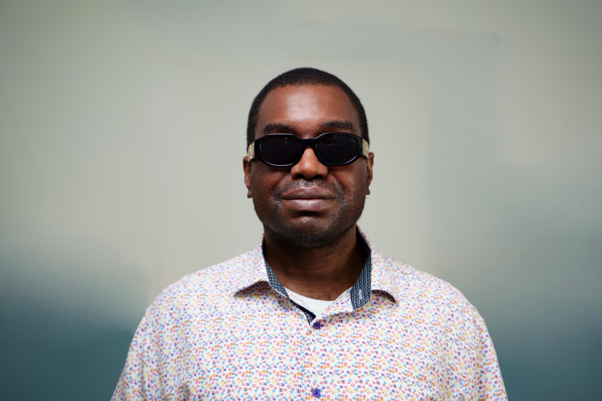 Professional portrait of Kevin E. Cartwright wearing dark glasses and a patterned dress shirt.