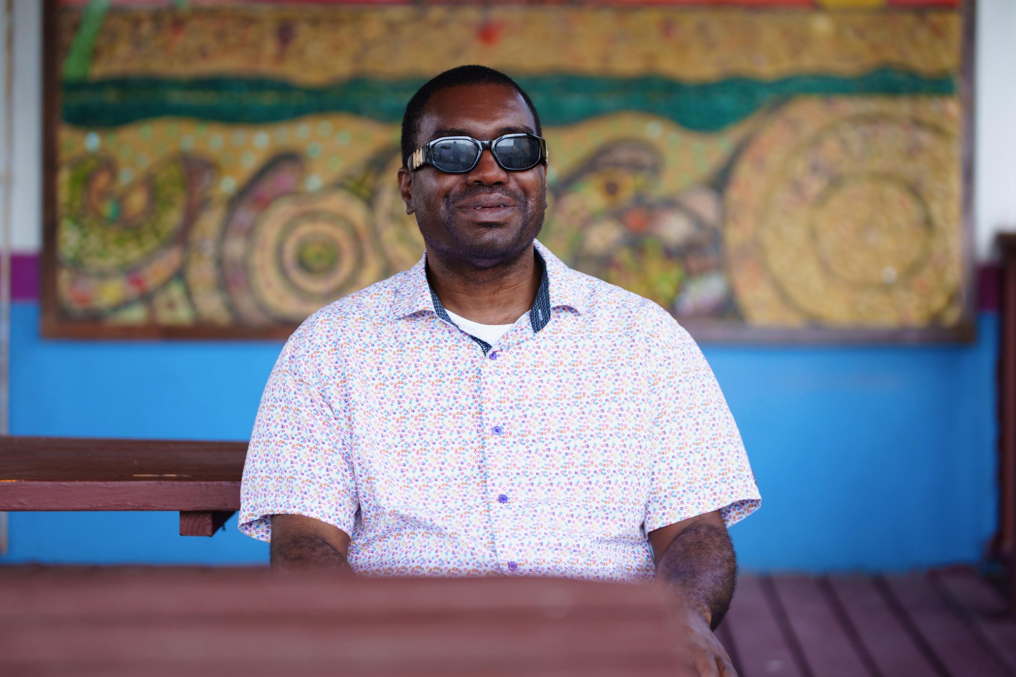 Kevin E. Cartwright outdoors in a professional portrait, wearing dark glasses and a patterned shirt.